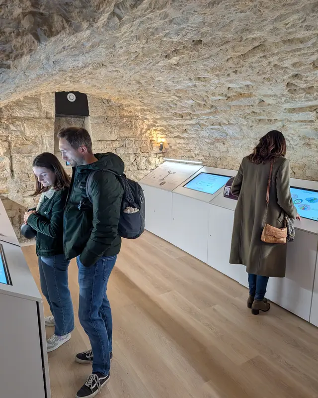 Dos visitantes explorando las exposiciones interactivas en las bodegas históricas abovedadas de Le Petit Musée du Vin, Lyon 7.°